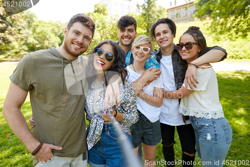 Image of friends taking picture by selfie stick at summer