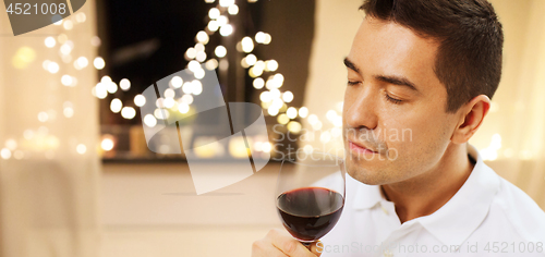 Image of happy man drinking red wine at home on christmas