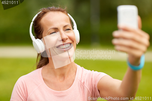 Image of woman in phones takes selfie by smartphone at park