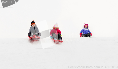 Image of kids sliding on sleds down snow hill in winter