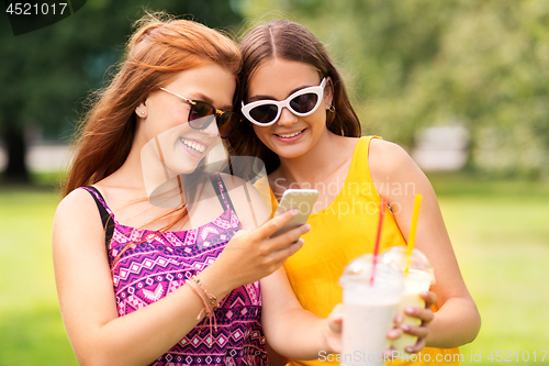 Image of teenage girls with smartphone and shakes in park