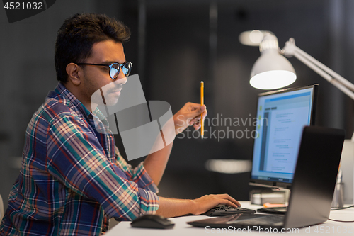 Image of creative man working with laptop at night office