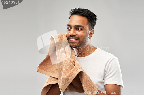 Image of smiling indian man with towel over grey background