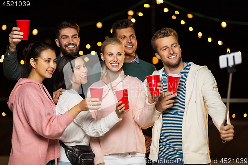 Image of friends with drinks taking selfie at rooftop party