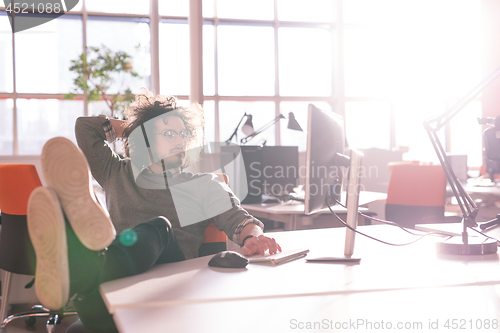 Image of businessman sitting with legs on desk