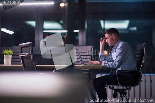 Image of man working on laptop in dark office