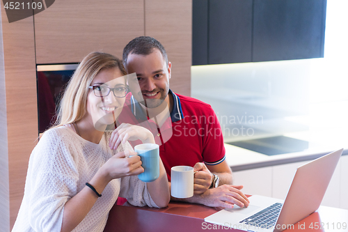 Image of couple drinking coffee and using laptop at home