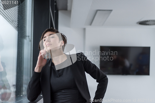 Image of Elegant Woman Using Mobile Phone by window in office building