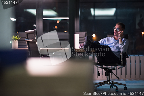 Image of businessman using mobile phone in dark office