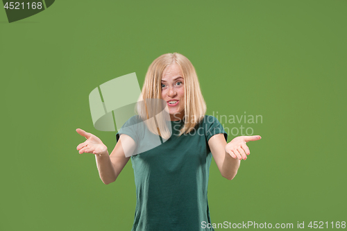Image of Beautiful female half-length portrait isolated on green studio backgroud. The young emotional surprised woman