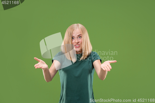 Image of Beautiful female half-length portrait isolated on green studio backgroud. The young emotional surprised woman