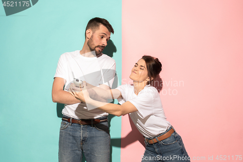 Image of young couple watching tv and fighting to get the remote control