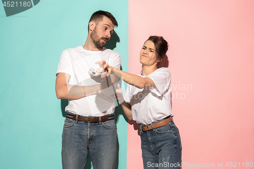 Image of young couple watching tv and fighting to get the remote control