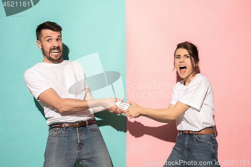 Image of young couple watching tv and fighting to get the remote control