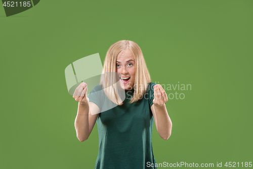 Image of Beautiful female half-length portrait isolated on green studio backgroud. The young emotional surprised woman