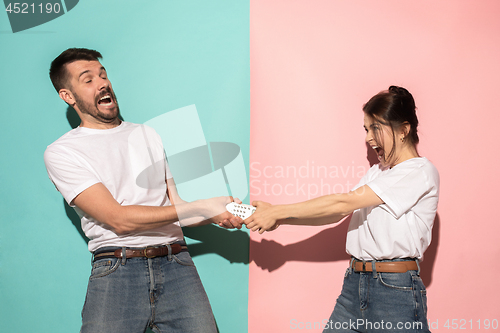 Image of young couple watching tv and fighting to get the remote control