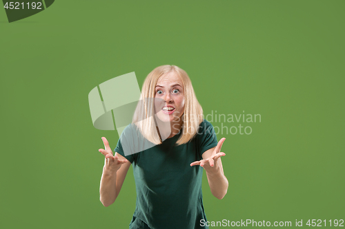 Image of Beautiful female half-length portrait isolated on green studio backgroud. The young emotional surprised woman