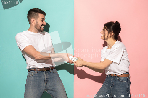 Image of young couple watching tv and fighting to get the remote control