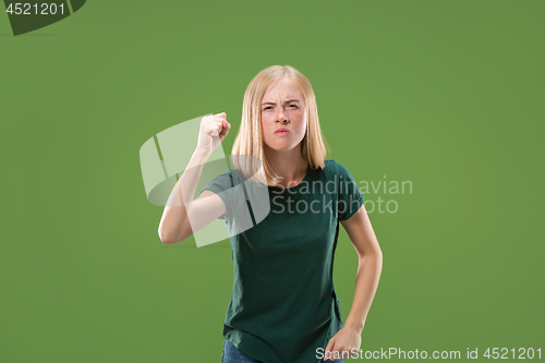 Image of Portrait of an angry woman looking at camera isolated on a green background