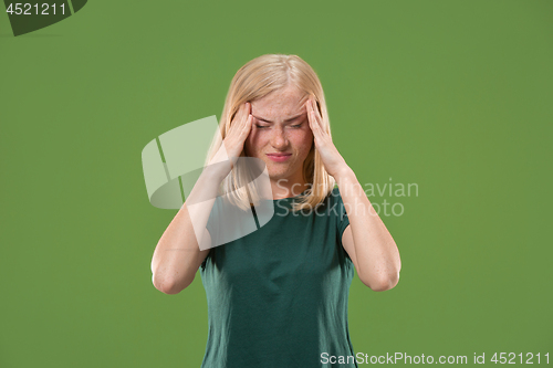 Image of Woman having headache. Isolated over green background.