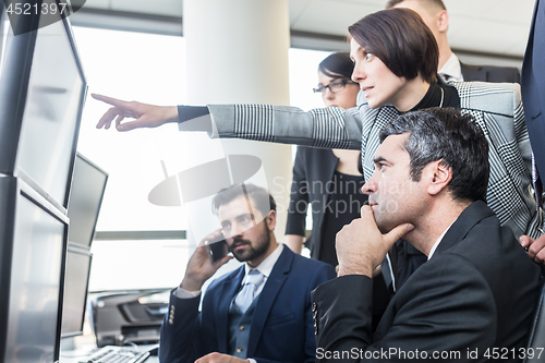 Image of Successful business team looking at trade data on computer screens in corporate office.