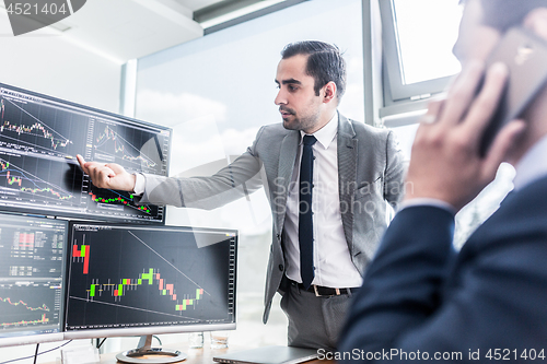 Image of Stock brokers looking at computer screens, trading online.