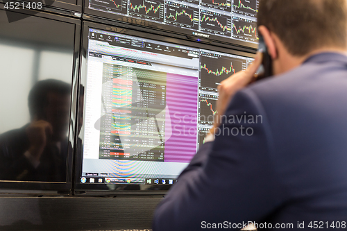 Image of Stock broker trading online, talking on mobile phone.