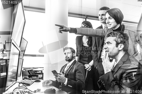 Image of Successful business team looking at trade data on computer screens in corporate office.