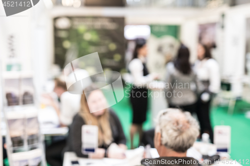 Image of Blured image of client consulting aobout product with saleswoman at business fair.