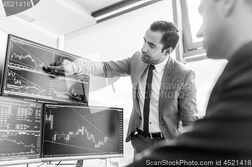 Image of Stock brokers looking at computer screens, trading online.