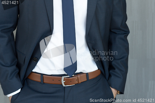 Image of Torso of a businessman standing with hands clenched in middle position in a classic navy blue suit.