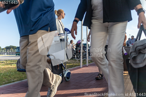 Image of Young woman transporting luggage from arrival parking to international airport departure termainal by luggage trolley.