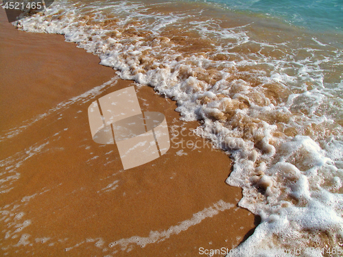 Image of Sea wave with white foam on the sandy beach