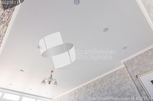 Image of Stretch ceiling in a room with a chandelier and spotlights, with natural light