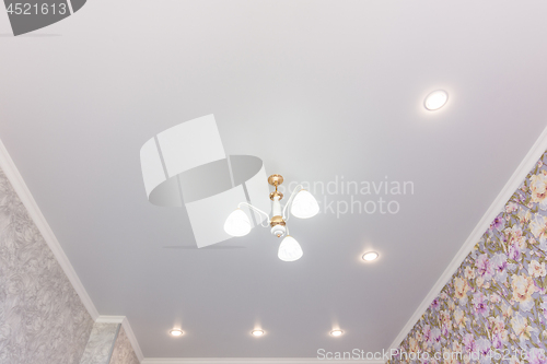 Image of Stretch ceiling in the room with a chandelier and spotlights