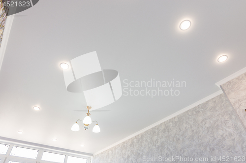 Image of Stretch ceiling in the room with a chandelier and spotlights