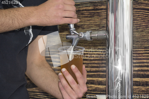 Image of Barmen filling plastic glass with light beer