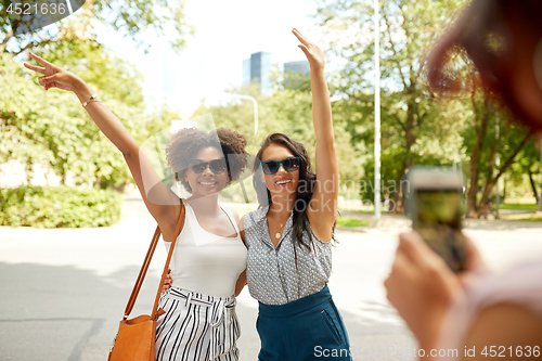 Image of woman photographing her friends in summer park