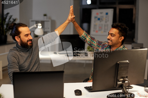 Image of creative team making high five at night office