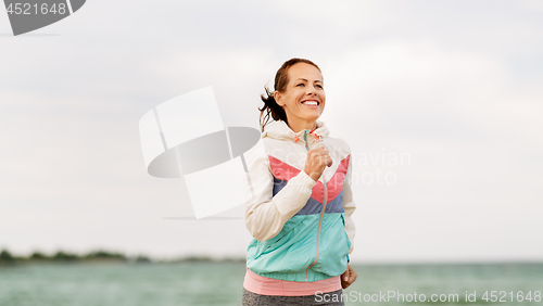 Image of smiling woman running along beach