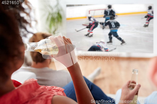 Image of friends watching ice hockey and drinking beer