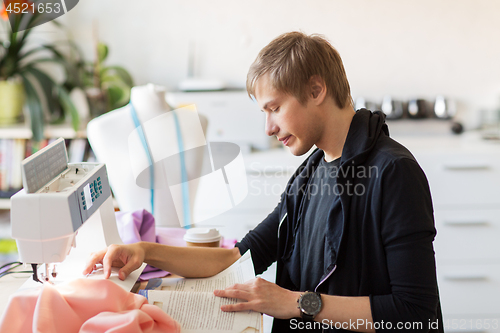 Image of fashion designer reading book at studio