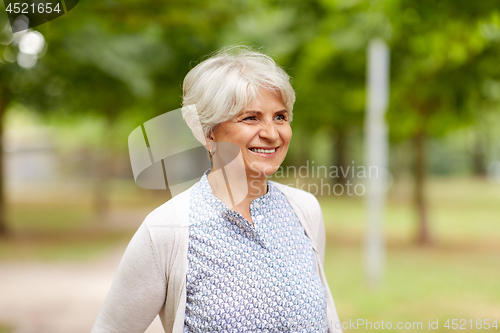 Image of portrait of happy senior woman at summer park