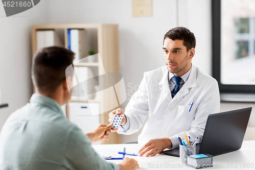 Image of doctor giving medicine to male patient at hospital