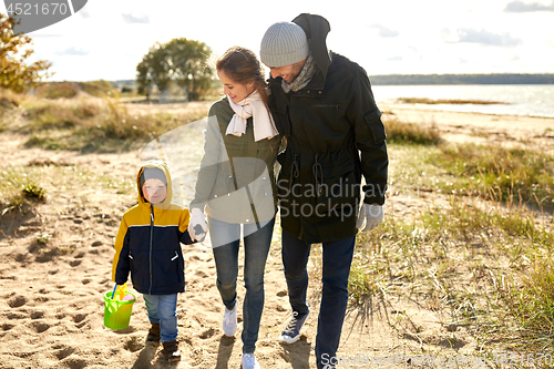 Image of happy family walking along autumn beach