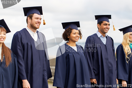 Image of happy students or bachelors in mortar boards