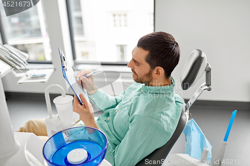 Image of patient filling application form at dental clinic