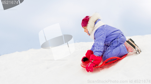 Image of girl sliding down on snow saucer sled in winter