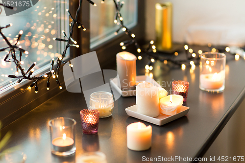 Image of candles burning on window sill with garland lights