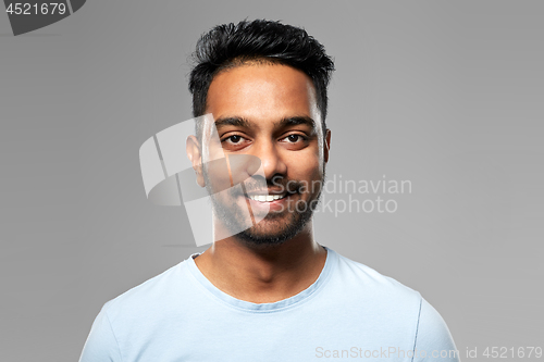 Image of smiling young indian man over grey background